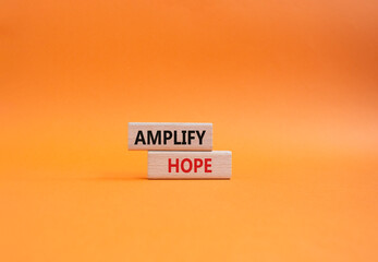 Amplify Hope symbol. Wooden blocks with words Amplify Hope. Beautiful orange background. Business...