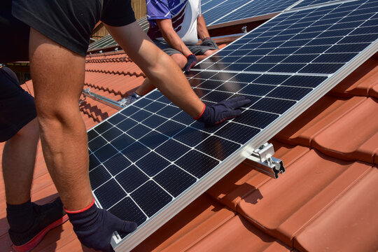Dachdecker beim Aufbau einer Photovoltaikanlage auf einem neu gedeckten Ziegeldach: Die Endklemmen f&uuml;r die der Solarmodule sind am Ende der Schienen befestigt