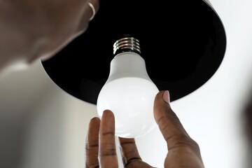 African woman replaces light bulb