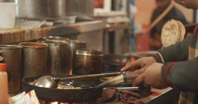 Man cooking street food Biryani on a busy street. Slow motion Biryani is a mixed rice dish, mainly popular in South Asia. It is made with rice, some type of meat chicken, goat, lamb, beef, prawn, or