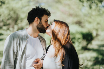 A young couple enjoys a carefree moment, kissing passionately in a sunny park on a weekend, dressed in casual clothing, portraying love and happiness.