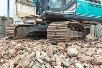 steel tracks of a mobile demolition crane standing on a mountain of stones