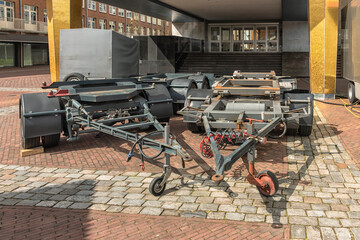 two steel chassis with rotating front wheels are parked outside on the street