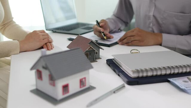 Male real estate agent is negotiating with a female client for a contractual sale of a house.