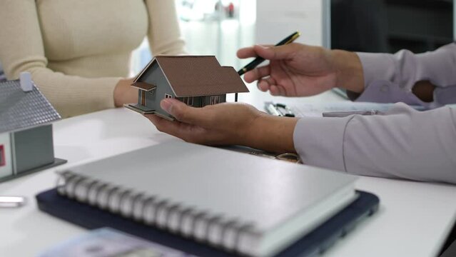 Male real estate agent is negotiating with a female client for a contractual sale of a house.