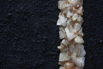 Citrine quartz fragments and black grunge surface, sandy effect. Vertical line of crystals.