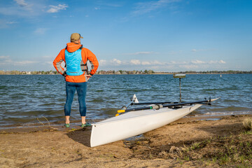 Senior male rower with his rowing shell on a beach of Boyd Lake in northern Colorado, early spring scenery