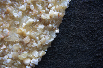 Citrine quartz fragments and black grunge surface, sandy effect. Empty space for text.