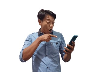Surprised young Asian man wearing a blue shirt holding a smartphone screen and emotionally reacting to online news isolated on white background. People Lifestyle Concept