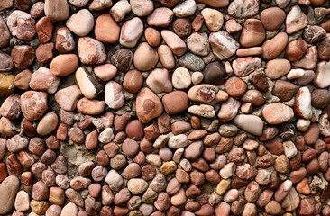 Brown colored natural organic shaped pebble rock stones material pattern isolated on horizontal ratio surface on full frame wall or flooring.