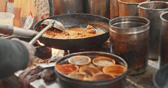 Man cooking street food fish on a busy street. Slow motion. South Asia.