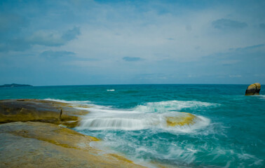 Aerial panorama of Thailand's verdant with blue and aquamarine the sea, and clouds shining by sunlight in the background.