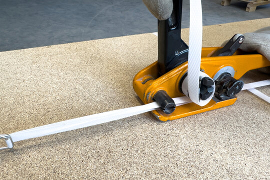 Manual packaging of cargo for shipping. Hand-operated polypropylene strapping tool. Packaging and shipping of goods packed in wooden crates. 