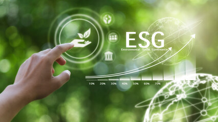 Businessman hand pointing at the word ESG with a green background. Three principles of responsible...