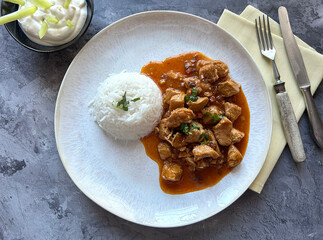 Traditional Hungarian Chicken Pörkölt with Rice, Bacon cubes, Paprika, gravy, herbs and sour cream dip with Pepper strips.
