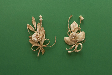 Decoration of straw on a green background. Branch with flowers. Boutonniere made out of straw....