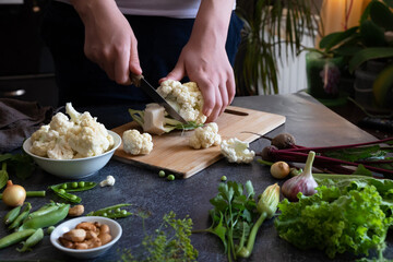 A woman cuts fresh cauliflower at the table