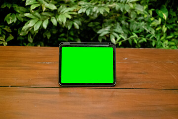 Green Screen iPad or Tablet on Wooden Table with Green Plants Background