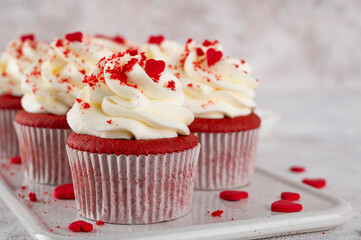 Red velvet cupcakes with cream cheese frosting and red sugar hearts. Delicious dessert for Valentines day. Selective focus, copy space.