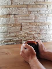 Cup of black tea in the hand of men . on a wooden and stone background