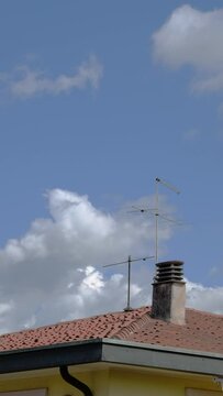 Time lapse, nuvole in movimento, tetto con comignolo e antenna, video verticale