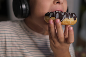 The simple joys of childhood captured as a child listens to music and enjoys a tasty donut,...
