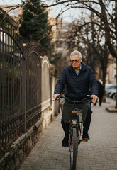 Active senior man riding bicycle on urban street in casual attire.
