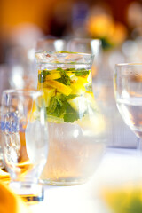 Summer refreshing homemade chilled drink with mint and citrus and ice. Nonalcoholic iced tea, lemonade with lemon. Chilled water with herbs