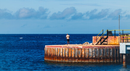 A man standing on a breakwater at the entrance to the sea.
