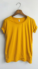 A sunflower yellow t-shirt displayed on an antique wooden hanger, isolated on a bright white backdrop. The bold color of the shirt 