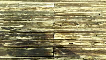 A weathered wooden deck made up of long, brown planks with visible wear and tear.  Some of the...
