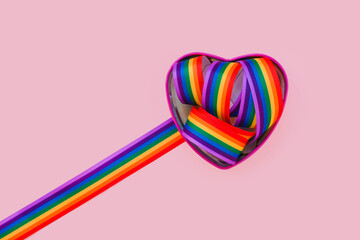 Lgbt rainbow ribbon in a heart shape on bright color background. Gay pride month, coming out day,...