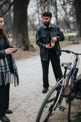 A male entrepreneur in a leather jacket using his mobile phone outdoors, a woman and bicycle in the background.