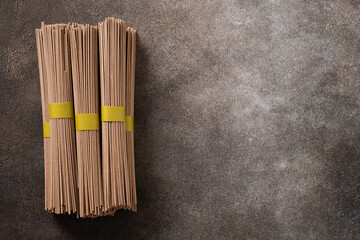 Uncooked buckwheat noodles soba on dark gray background. View from above. Space for text. Healthy...