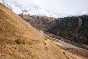 The Contrast of Golden Hills and Verdant Valleys Under the Snowy Peaks of the Caucasus
