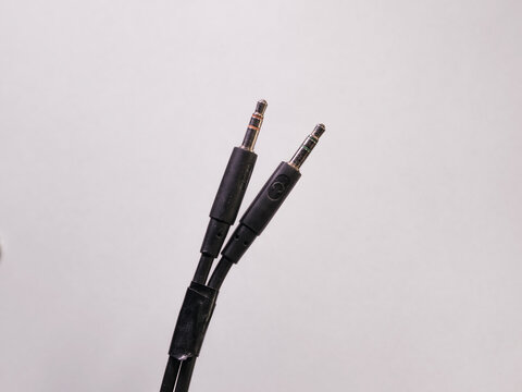 Close-up view of gold-plated audio and microphone cables on a white studio background.