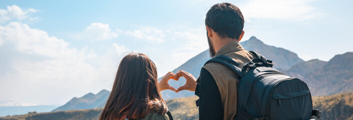 A loving traveling couple with backpacks makes a heart with their hands. stock photo