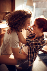 Happy couple embracing and kissing in sunny kitchen