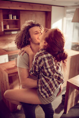 Happy couple embracing and kissing in sunny kitchen