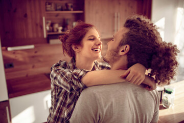 Happy couple embracing and kissing in sunny kitchen