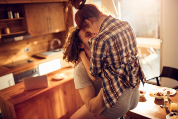 Romantic couple kissing in cozy home kitchen