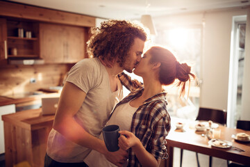 Romantic couple kissing in cozy home kitchen