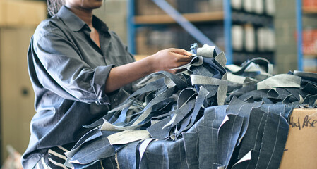 A hand holding shredded raw denim fabric in a denim factory. Industrial fabric and fashion...