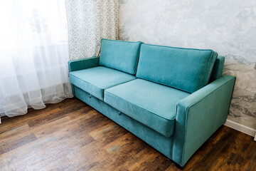 Electric blue couch as a fixture in a living room, located next to a window