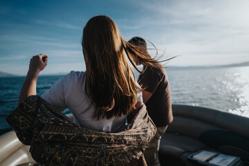 Two friends experience joy and relaxation during a boat trip on a beautiful, sunny day, embodying a...