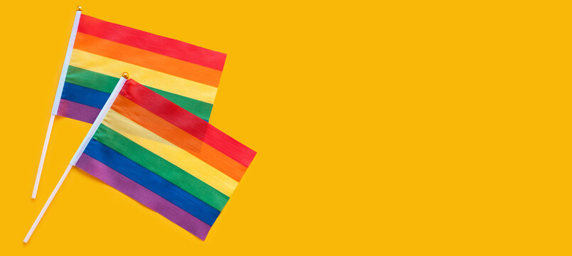 LGBT rainbow flag flat lay on yellow color background. gay marriage, human rights, june parade, lgbtq proud history month concept, coming out day. top view, place for text or logo