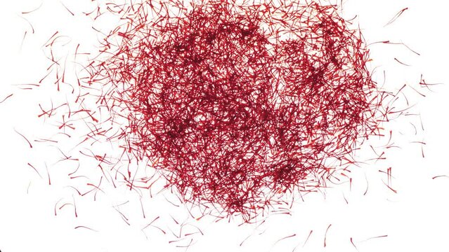 Red saffron threads falling on a white surface