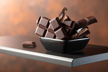Broken dark chocolate bar in small black dish.