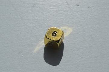 Gold D6 die showing 6 in sunlight on white background
