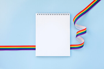 Blank mock up notebook on rainbow ribbon LGBTQ flag background. Proud pride month parade, gay marriage, coming out day concept, human rights, tolerance concept. Flat lay, top view place for text logo